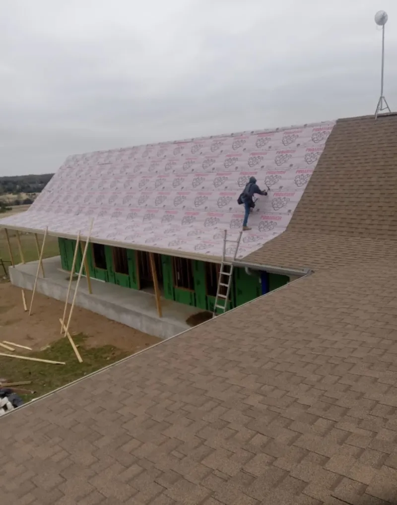 Worker preparing underlayment for a metal roof installation in Palmer